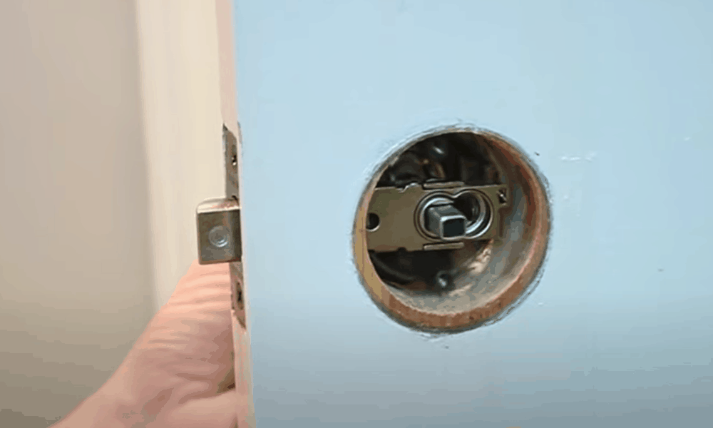 Insert one half of the doorknob in through the latch